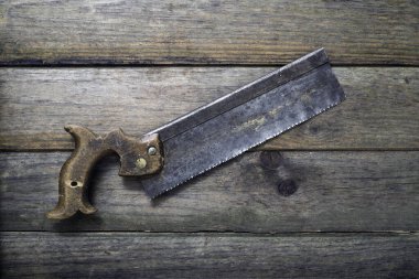 Eski paslı çapraz el testeresi testeresi ahşap arka planda izole edilmiş.