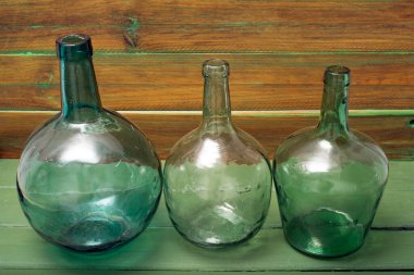 Ahşap arka planda üç şişe yeşil cam.