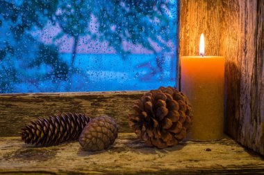 Pencere pervazında mum ve çam kozalakları vardı. Noel süsü