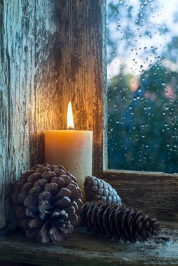 Pencere pervazında mum ve çam kozalakları vardı. Noel süsü