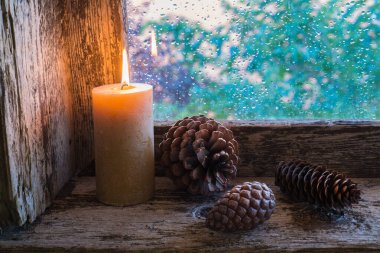 Pencere pervazında mum ve çam kozalakları vardı. Noel süsü