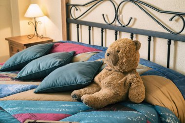 Happy teddy bear relaxing on comfortable bed