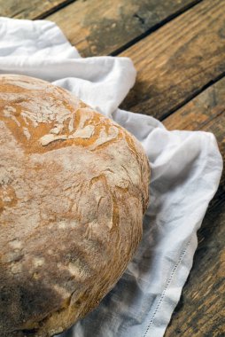 Tahta masadaki beyaz masa örtüsü üzerinde bir somun ekmek.