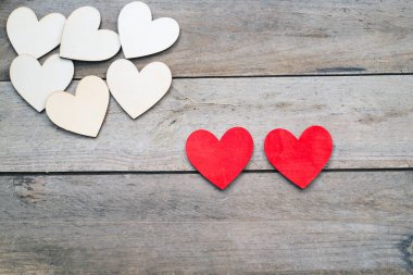 Ahşap bir arka planda iki kırmızı kalp. Bir köşede beyaz kalpler