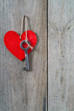 Kırmızı bir kalbe ip takılmış bir anahtar. Ahşap arkaplan