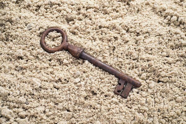 Old key in the sand