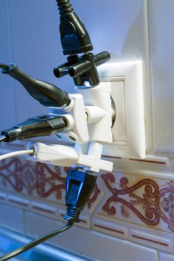 Çok kullanılan bir elektrik prizinin yakın plan görüntüsü. Birden fazla cihaz takılı, güç kullanımını gösteriyor..