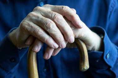 Yaşlı ellerin ahşap bir bastonu kavraması, yaşlanmayı, bağımlılığı ve yaşlı bakımını sembolize ediyor. Kıdemli bireylerin hayatlarındaki haysiyet, bilgelik ve şefkat temalarını vurgulamak.