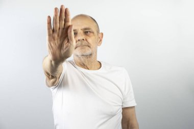 Beyaz gömlekli yaşlı adam, dur ya da dur hareketini göstermek için elini kaldırıyor. İletişim, reddetme, sınırlar veya anlaşmazlık için kavramsal görüntü, tarafsız bir arkaplanda izole edilmiş..