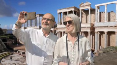 Güneşli bir günde tarihi bir Roma yerleşkesini keşfeden mutlu yaşlı çift. Tatillerinde fotoğraf çekiyorlar ve anılar yaratıyorlar, neşe, arkadaşlık ve kültürel tarihin takdir edilmesini yansıtıyorlar..