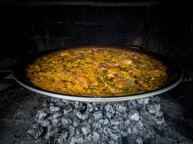 Yakacak odun üzerine İspanyol usulü paella. Yakından geniş açılı.