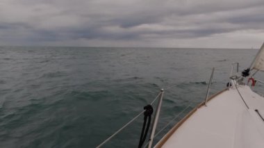 Yelkenli, bulutlu gökyüzünün altında ağır çekimde ilerliyor.