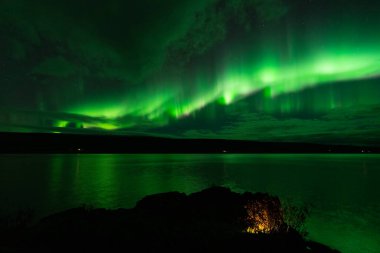 Karanlık bir gecede gölün üzerinde Aurora Borealis
