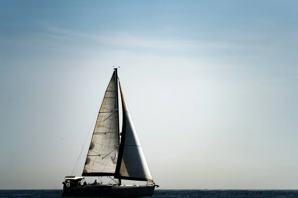 Profile of sailboat silhouette over ocean and white sky for text