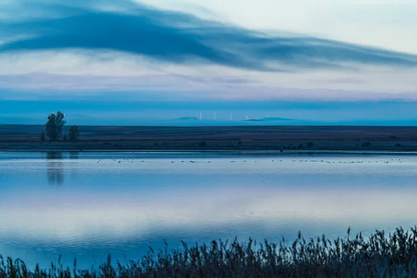 空に湾曲した雲と湖の上に夜明け — ストック写真