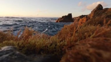 Gün batımında kameranın üzerinde dalga kırılıyor.