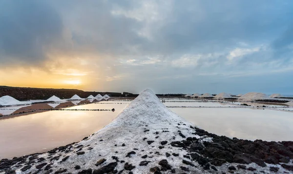 Pile of salt ahead of colorful salt mines at dawn