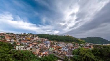 Brezilya 'nın işçi sınıfı mahallesindeki parlak renkli, basit evlerle dolu bir tepenin üzerinden hızla geçen bulutları izleyin..