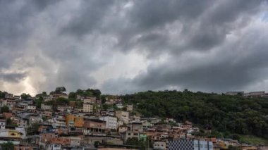 Gecekondularla kaplı bir tepenin üzerindeki fırtına bulutlarının kararmasını izleyin. Bu yoksul, ihmal edilmiş topluluklar çoğu zaman unutulur ve kendi başlarının çaresine bakarlar..