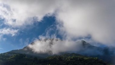 Şafak vakti sisle kaplı kayalık bir dağın şaşırtıcı hızlandırılmış görüntüleri sol taraftan gelen güneş ışınlarıyla yavaş yavaş kayboluyor..