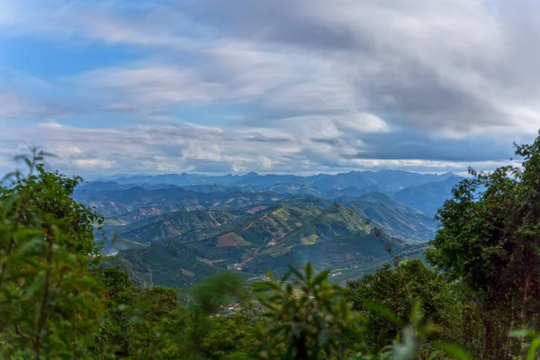 A breathtaking landscape of coffee mountains seen from above, with green fields stretching to the horizon, and clouds moving in long exposure under the cloudy sky. Perfect for travel or nature designs