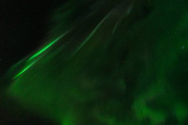 Koyu siyah gökyüzü yeşil aurora borealis ile kaplıdır.