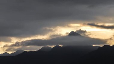 Bulutların hızlanması granit yuvarlak dağ zirvesinin etrafında türbülans yaratıyor, gün batımında ufkun üzerinde duruyor..