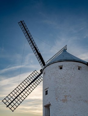 Gün batımında gökyüzüne karşı ahşap bıçakları olan tek bir klasik yel değirmeni.