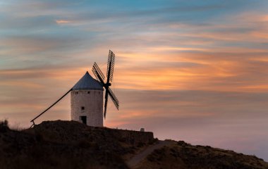 Güneş batarken tepenin üzerinde ıssız bir yel değirmeni var.