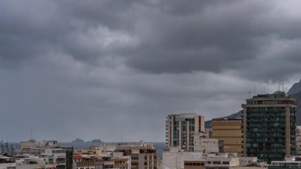 随着时间的流逝 风暴云彩在沿海城市上空飘扬 海面上形成了一个独立的岩层 周围还有建筑物 — 图库视频影像