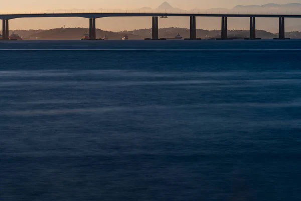 長い露出写真は 夕暮れ時の銀色の水滴に対してニテロイ橋を展示し 時間の経過を強調しています — ストック写真