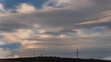 Güzel zaman dilimi videosu, siluetli iletişim antenleri ve metin alanlarıyla bir dağın zirvesinde dönen devrimci bulutları içerir.