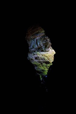 Yürüyüşçüler karanlık bir mağaradan aydınlığa çıkar, mağaranın içinden, girişi ışığı çerçeveler..