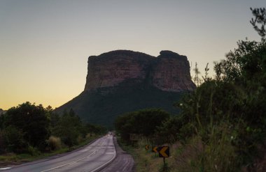 Peder Ignacios Hill 'in dağ siluetiyle alacakaranlık manzarası, yolda hareket eden araçlar ve metin için yer.