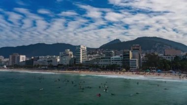 Rio de Janeiro 'daki Ipanema plajında dalgalar üzerinde sörf yapan bilinmeyen sörfçüler ve arka planda ikonik İsa heykeli.