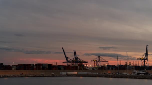 バレンシアの商業ドックのサンセット 船積みコンテナ クレーン 青とオレンジ色の色の空 — ストック動画