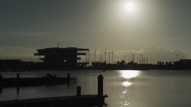 Valencia marinasında arkadaşlarla gün doğumunun tadını çıkarmak, sabah güneşinin yansıması ve bir tekne manzarayı güzelleştirir..