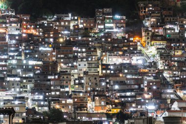 Dar sokaklar labirenti ve sıkıca sarılmış evleri olan bir tepenin üzerinde kalabalık bir gecekondu mahallesinin gece manzarası..