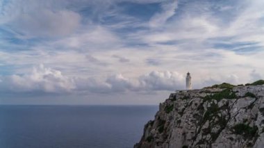 Zaman ayarlı bir video kayalıklarda, sakin bir denizin arka planında hızla hareket eden bulutlar ve metin için yer olan görkemli bir deniz feneri içerir..