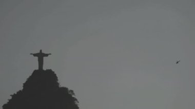 Kurtarıcı İsa 'nın etrafında alacakaranlıkta, gökyüzünün altında fotokopi uzayı ile uçan helikopter..