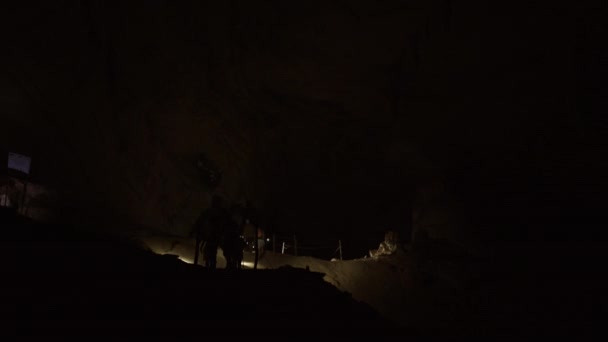 Large Group Unrecognizable People Walking Dark Cave Illuminating Path Flashlights — Stock Video