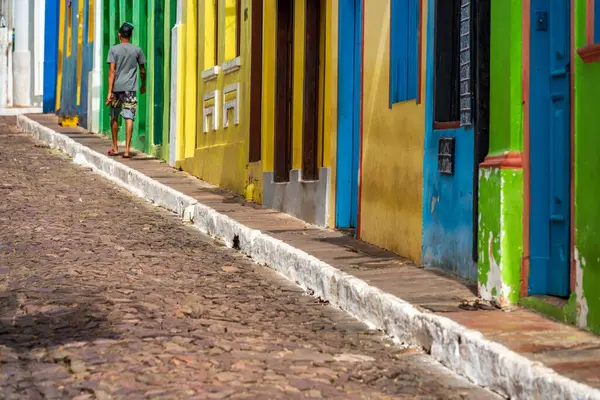 A person walks along a cobblestone path lined with colorful houses.