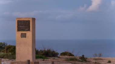 Jules Verne anıtının Formentera uçurumunda, dünyanın sonu olarak tasvir edilen deniz fenerinin yakınındaki bulutların ve turistlerin geçişi..
