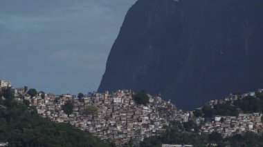 Askılı planörler, tepedeki kalabalık Rocinha gecekondularının üzerinde Pedra da Gavea 'nın yanından uçar..