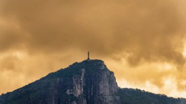 Rios Christ Redeemer dağının üzerinde hareket eden turuncu bulutların çarpıcı zamanlaması ve gökyüzünde dönen helikopter izleri. Metin için uygun alan.