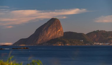 Rio 'daki Sugarloaf Dağı' nın çarpıcı alacakaranlık manzarası ipeksi su, parlayan bulutlar ve tekne yollarıyla. Metin alanı için ideal.
