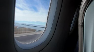 Slow-mo video shows wing flaps and airbrakes in action on planes window view during landing.