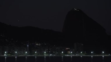 Ünlü Copacabana plajı, görkemli Sugarloaf dağı ve yıldızların altında bir uçağın yer aldığı göz kamaştırıcı bir gece videosu..