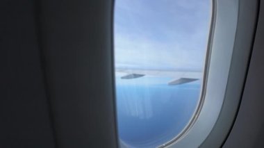 Uçak kanadı ve gökyüzü kamera düzlem penceresinden geri çekilirken görünür, metin alanı sağlar.
