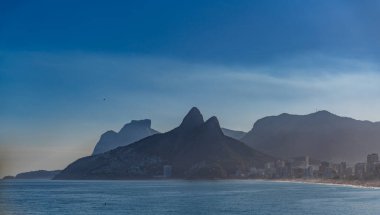 Rio de Janeiros ikonik dağları okyanusun üzerindeki alacakaranlık gökyüzüne karşı duruyor.